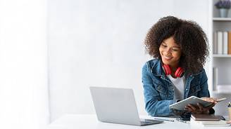 Imagen de un estudiante en su cuarto frente a una computadora, sonriendo por haber sido aceptado a un programa de educación virtual